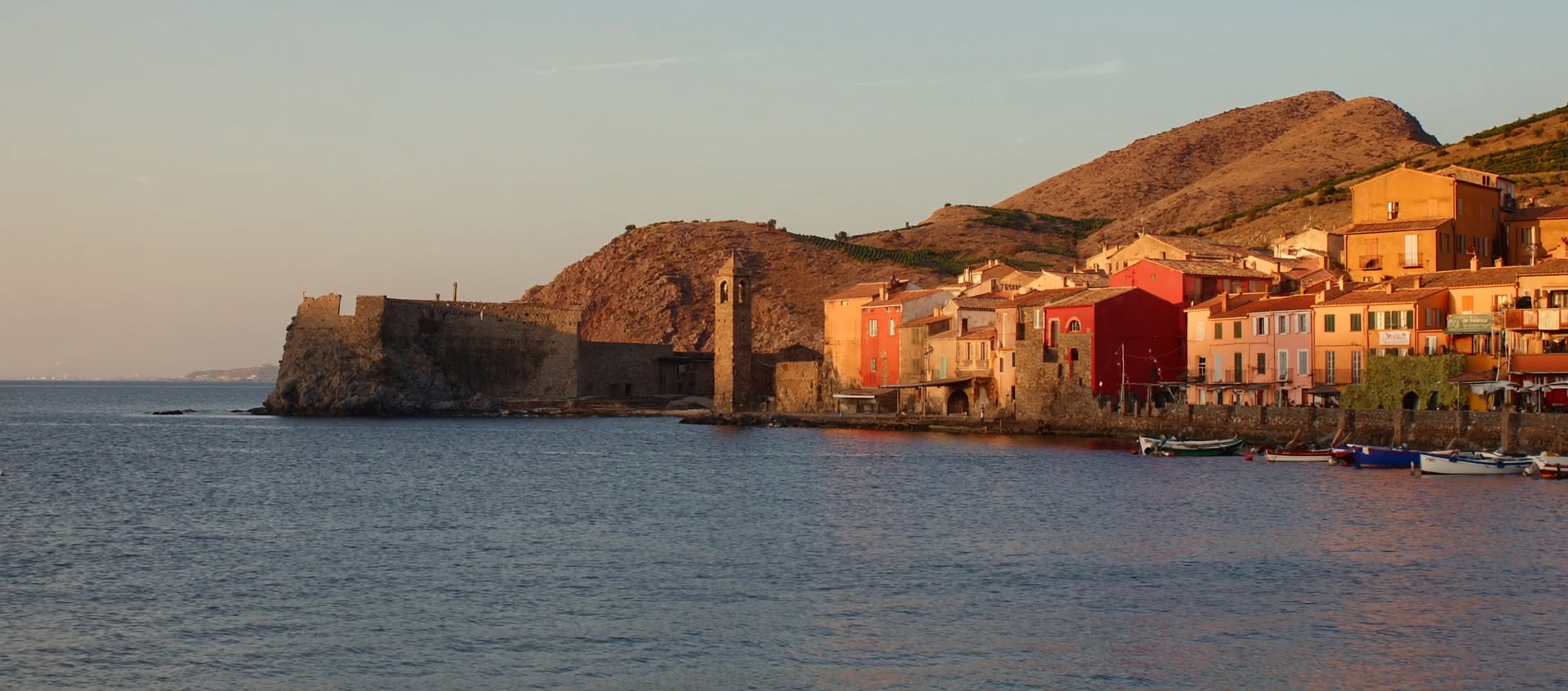 Village de la côte catalane au coucher du soleil : clocher, maisons ocre et petit port sur la Méditerranée (illustration)